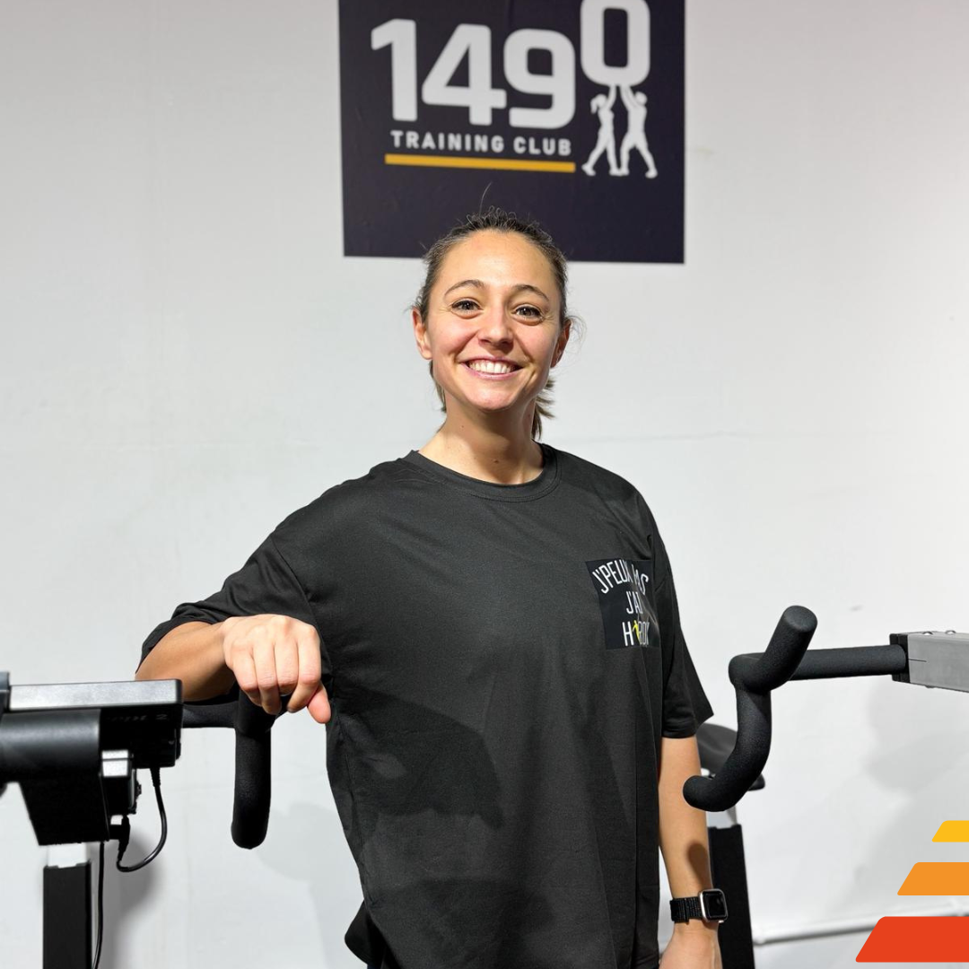 Portrait de Charline Vanden Berghe, coach du 1490 Training Club, souriante, portant une tenue sportive, sur fond blanc.